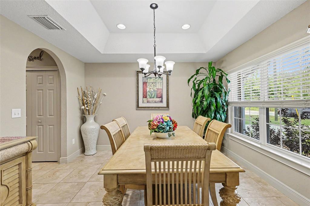 A dining room with a tray ceiling, chandelier, wooden table, and tile flooring — 4 MALAUKA RADIAL PASS, OCKLAWAHA, FL