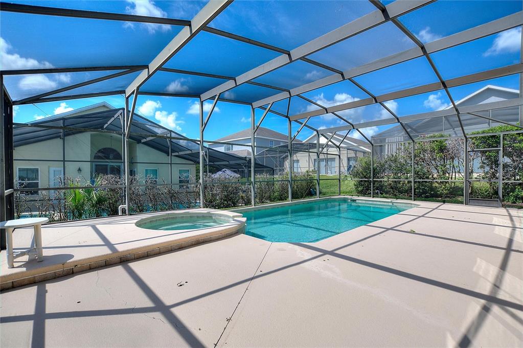 A screened-in patio features a swimming pool and an attached hot tub on a concrete deck — 16616 PALM SPRING DRIVE, CLERMONT, FL