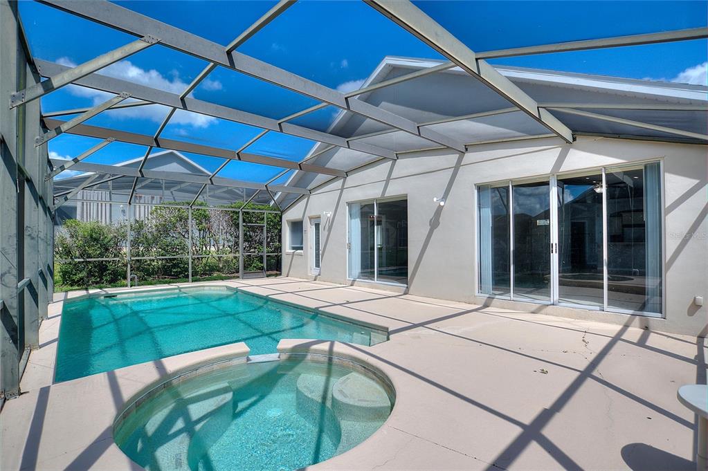 A screened-in patio featuring a swimming pool, a circular spa, and sliding glass doors — 16616 PALM SPRING DRIVE, CLERMONT, FL