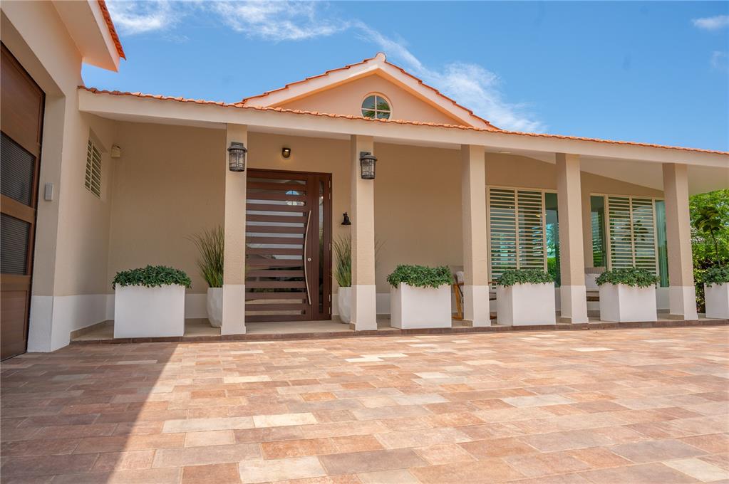 A covered patio features two wooden rocking chairs, potted plants, and light-colored tile flooring — 302 CAMINO DE LOS CEDROS, DORADO, PR