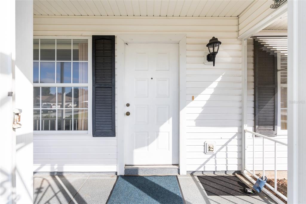 A white front door with black shutters and a porch light on a house exterior — 6511 SW 85TH STREET, OCALA, FL