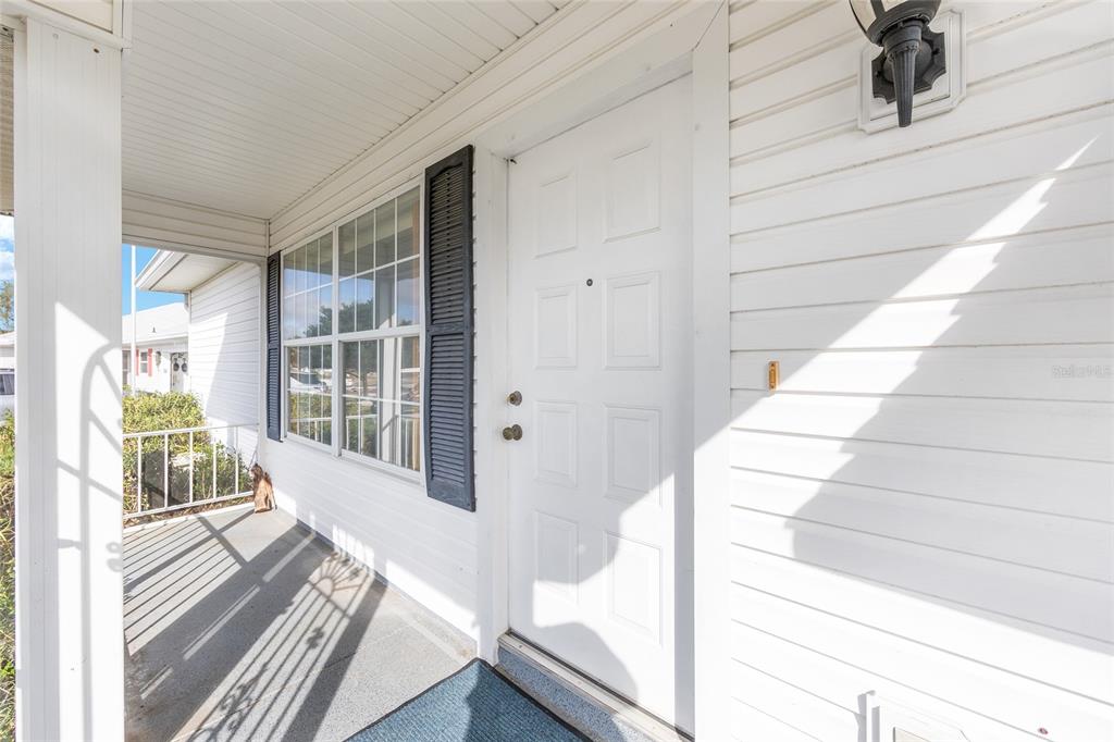 A white front door with a porch and a window with dark shutters — 6511 SW 85TH STREET, OCALA, FL