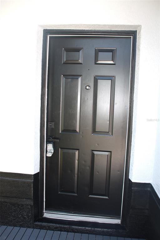 A black six-panel front door with a lockbox is set in a white exterior wall — 2537 JASMINE TRACE DRIVE, KISSIMMEE, FL