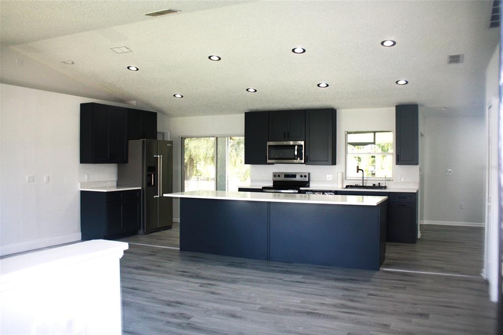 A modern kitchen features dark cabinetry, a large central island, and light-colored countertops — 2537 JASMINE TRACE DRIVE, KISSIMMEE, FL