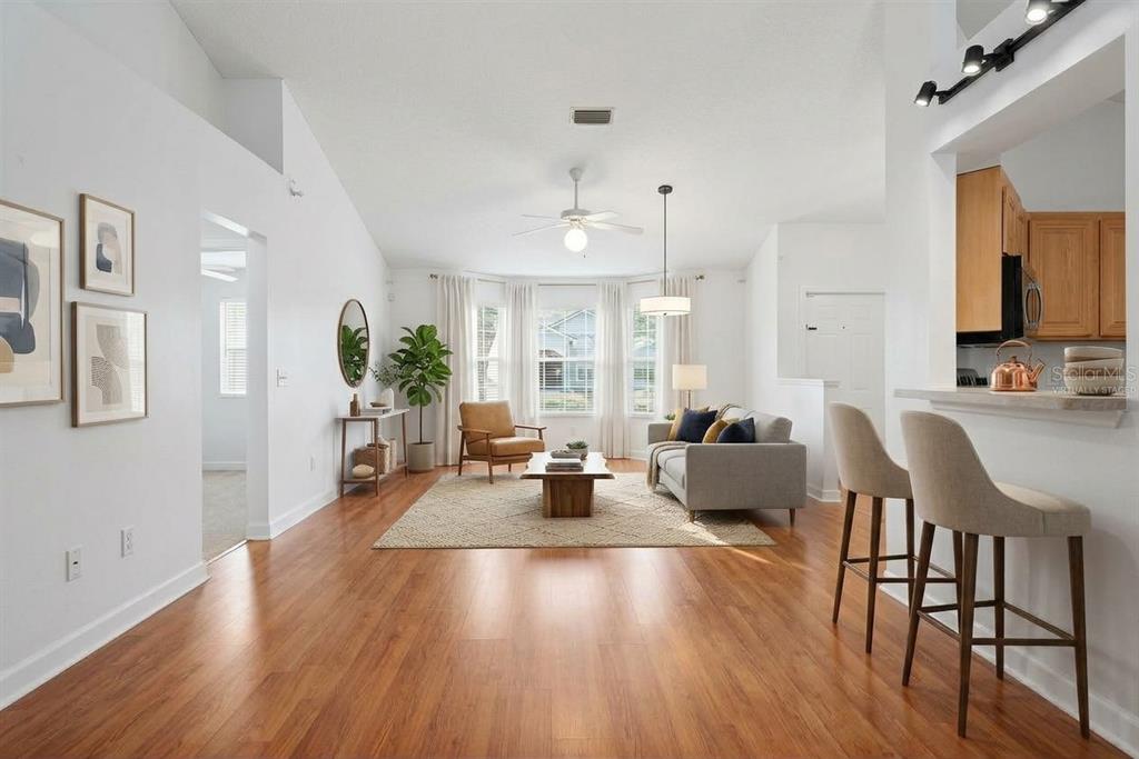 A living room with light gray walls, wood-look flooring, a ceiling fan, and a kitchen pass-through — 4308 NW 35TH TERRACE, GAINESVILLE, FL