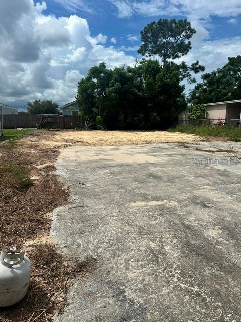 A concrete slab sits in front of a cleared dirt lot with trees in the background — 6604 TRALEE AVENUE, NEW PORT RICHEY, FL