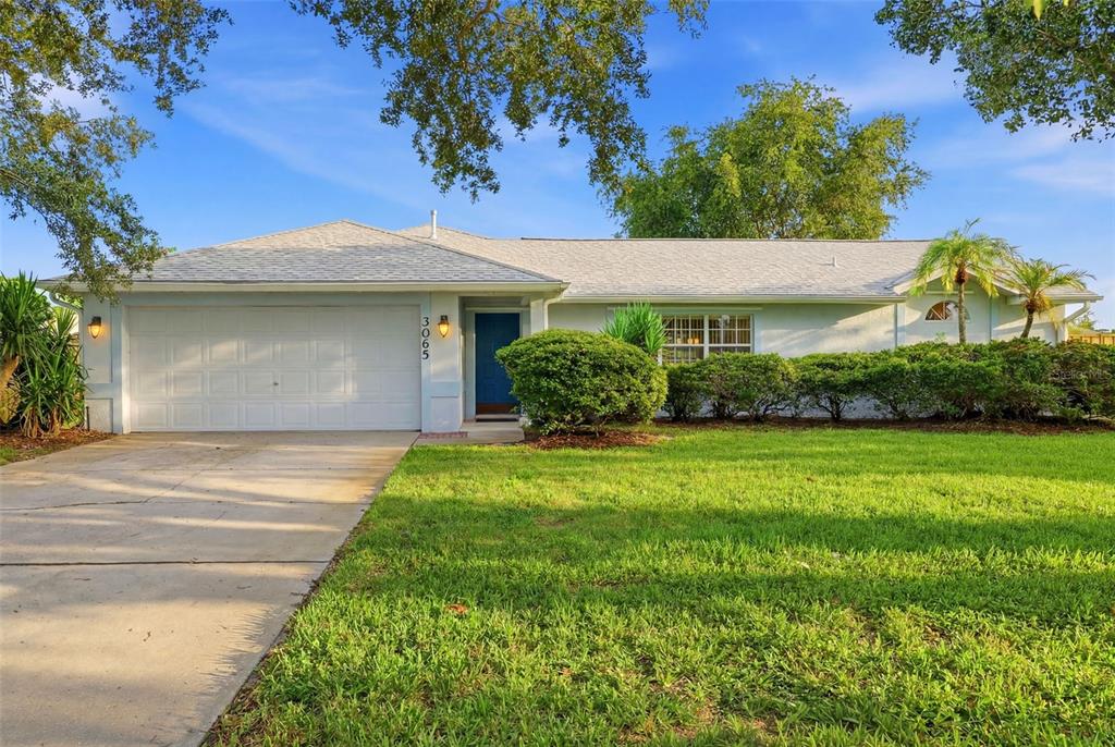 A single-story house with a white garage and a blue front door at sunset — 3065 PINEDA CROSSING DRIVE, MELBOURNE, FL