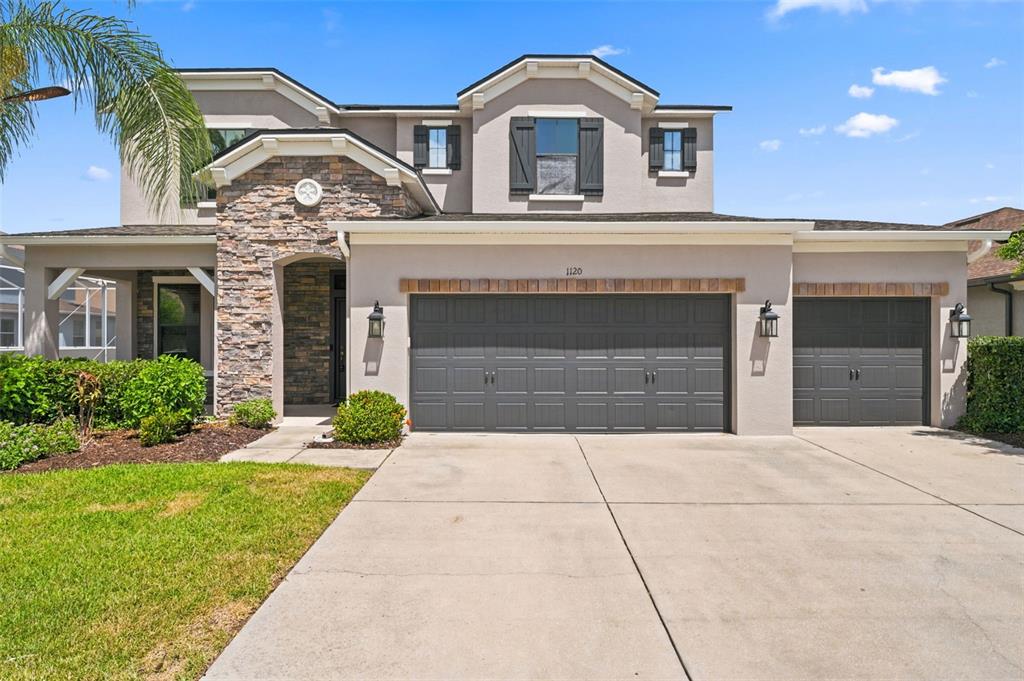 A two-story suburban house features a stone facade, a three-car garage, and dark shutters — 1120 MAZA PLACE, TRINITY, FL