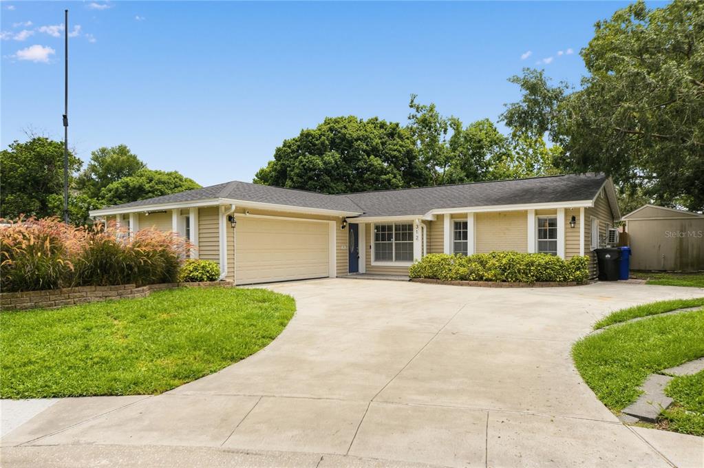 A single-story house with light yellow siding, a two-car garage, and a concrete driveway — 312 HORMIGAS STREET, OCOEE, FL