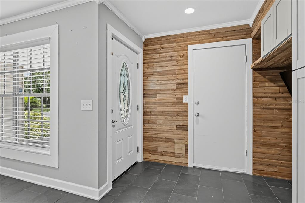An entryway features a white front door, a wood-paneled wall, and dark gray tile flooring — 312 HORMIGAS STREET, OCOEE, FL