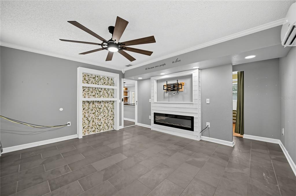 A living room features gray tile flooring, a ceiling fan, a fireplace, and built-in shelving — 312 HORMIGAS STREET, OCOEE, FL