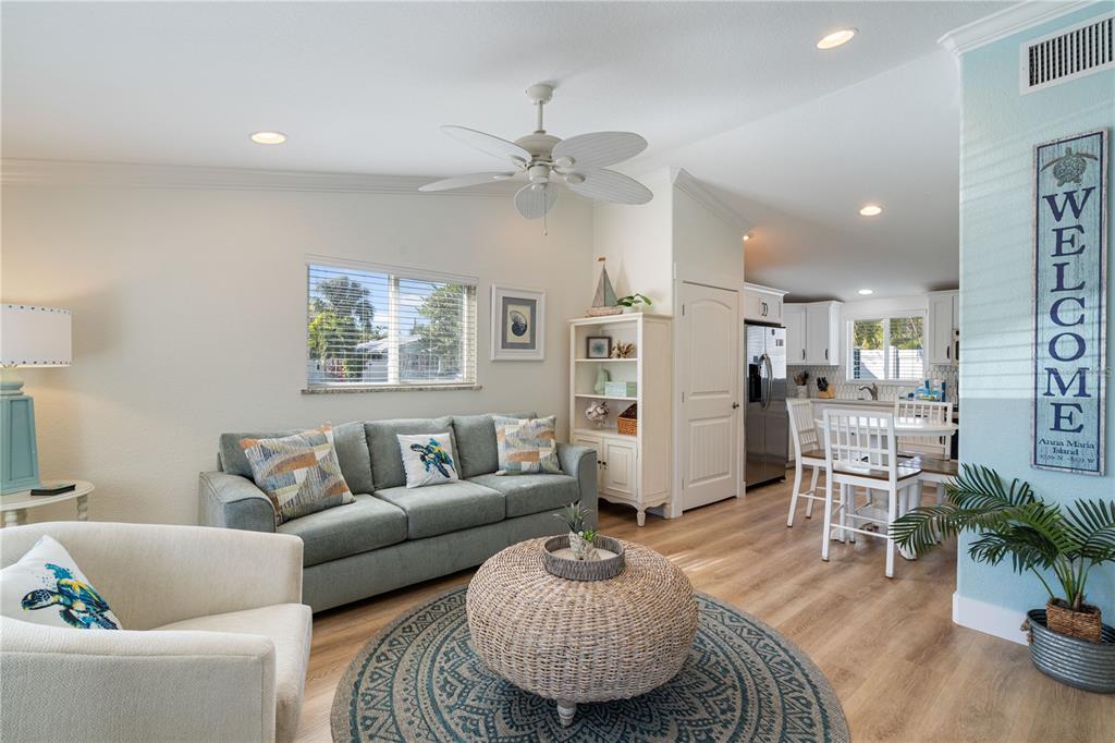 A living room features a grey sofa, wicker coffee table, and an open kitchen area — 3009 AVENUE E UNIT A, BRADENTON BEACH, FL