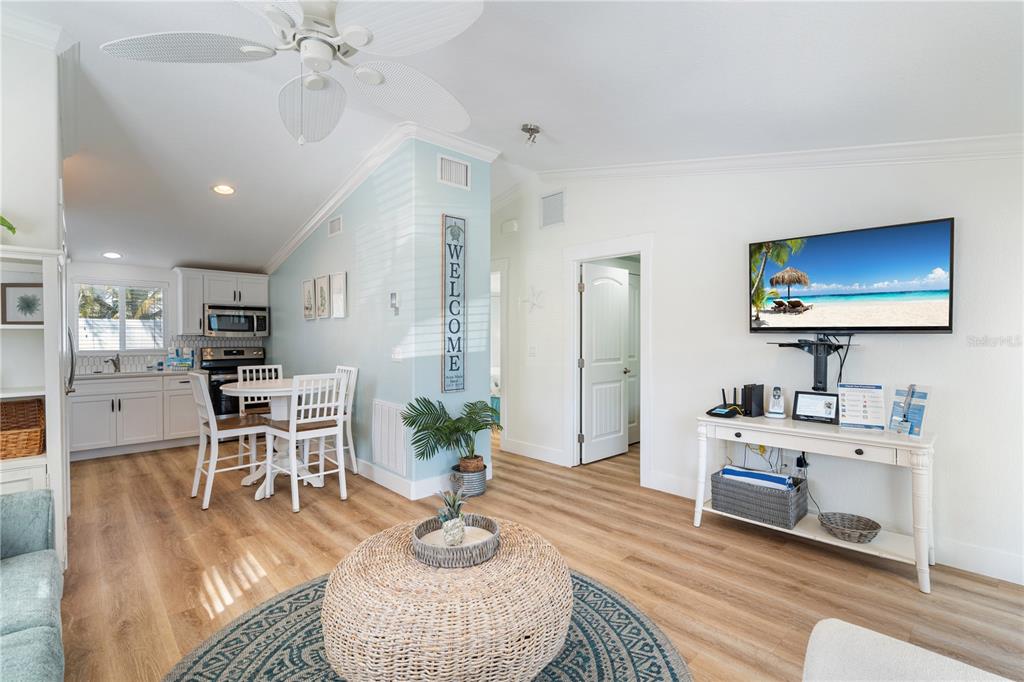 A living room and dining area feature light wood flooring, a ceiling fan, and white cabinetry — 3009 AVENUE E UNIT A, BRADENTON BEACH, FL