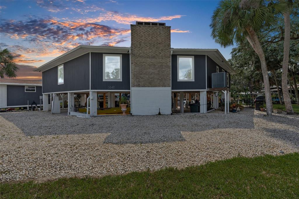 A stilt house with a gravel driveway and an attached shed under a blue sky — 5648 S GARCIA ROAD, HOMOSASSA, FL