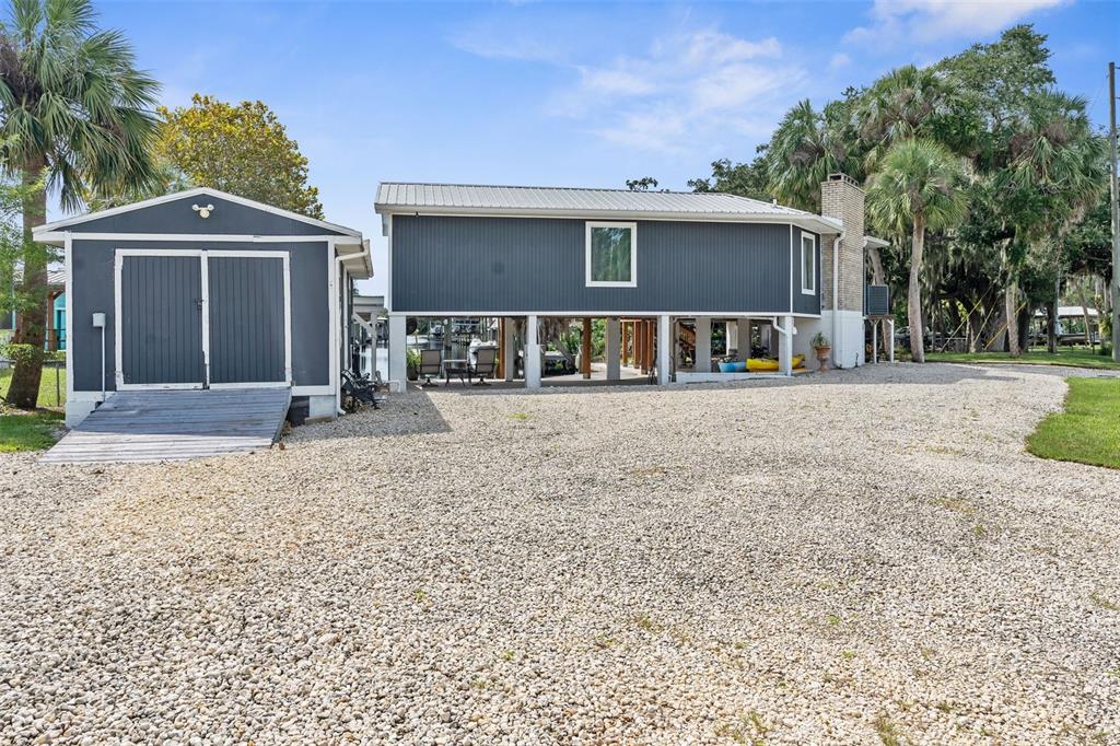 A covered concrete patio features exposed wood ceiling panels, support columns, and a waterfront view — 5648 S GARCIA ROAD, HOMOSASSA, FL