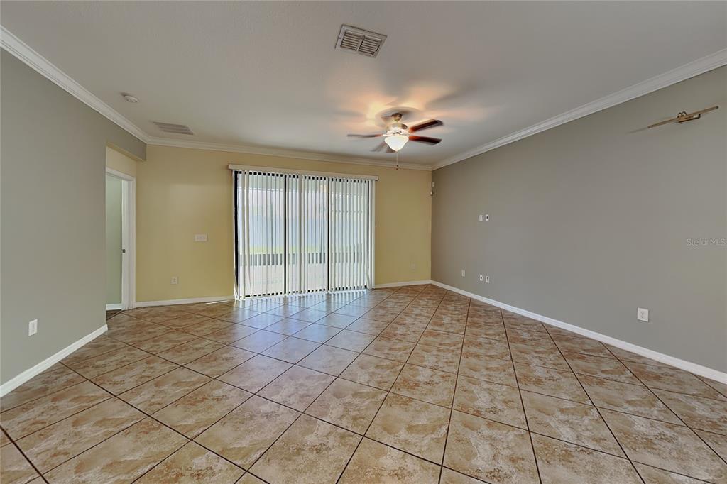 An empty living room features beige walls, a ceiling fan, and diagonal tan tile flooring — 11020 WHITTNEY CHASE DRIVE, RIVERVIEW, FL