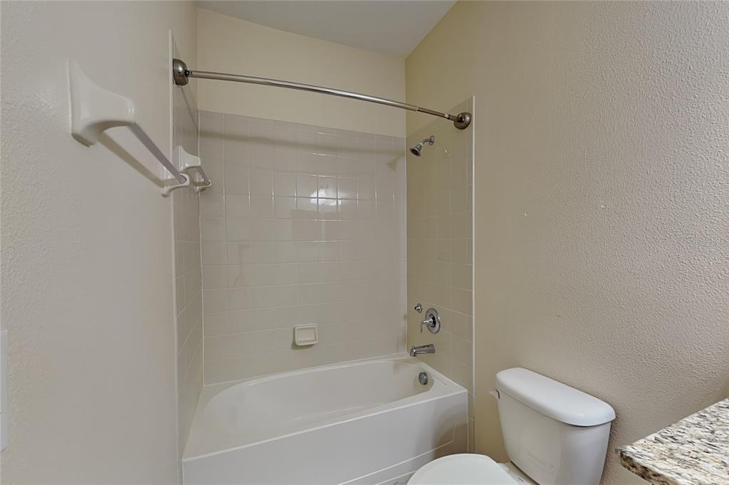 A bathroom features a white bathtub with a tiled surround, a showerhead, and a toilet — 11020 WHITTNEY CHASE DRIVE, RIVERVIEW, FL