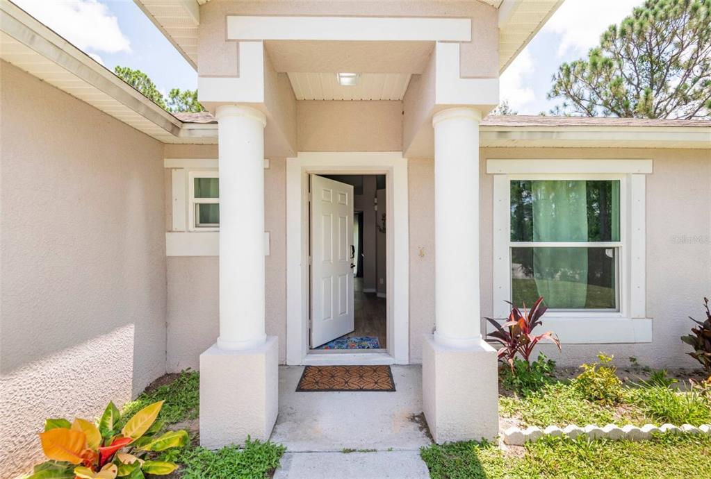 A single-story house with a beige stucco exterior, a garage, and a front walkway — 2471 QUINCY AVENUE SE, PALM BAY, FL