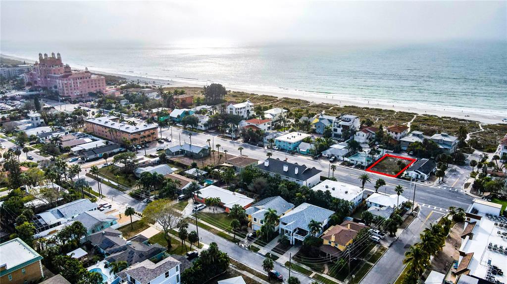 An aerial view shows a vacant lot situated between two residential buildings near a road — 3614 GULF BOULEVARD, ST PETE BEACH, FL