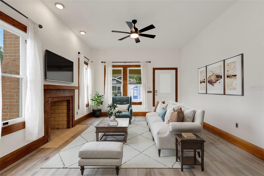 A living room features a brick fireplace, white sofa, wood trim, and a ceiling fan — 711 E LIME STREET, LAKELAND, FL