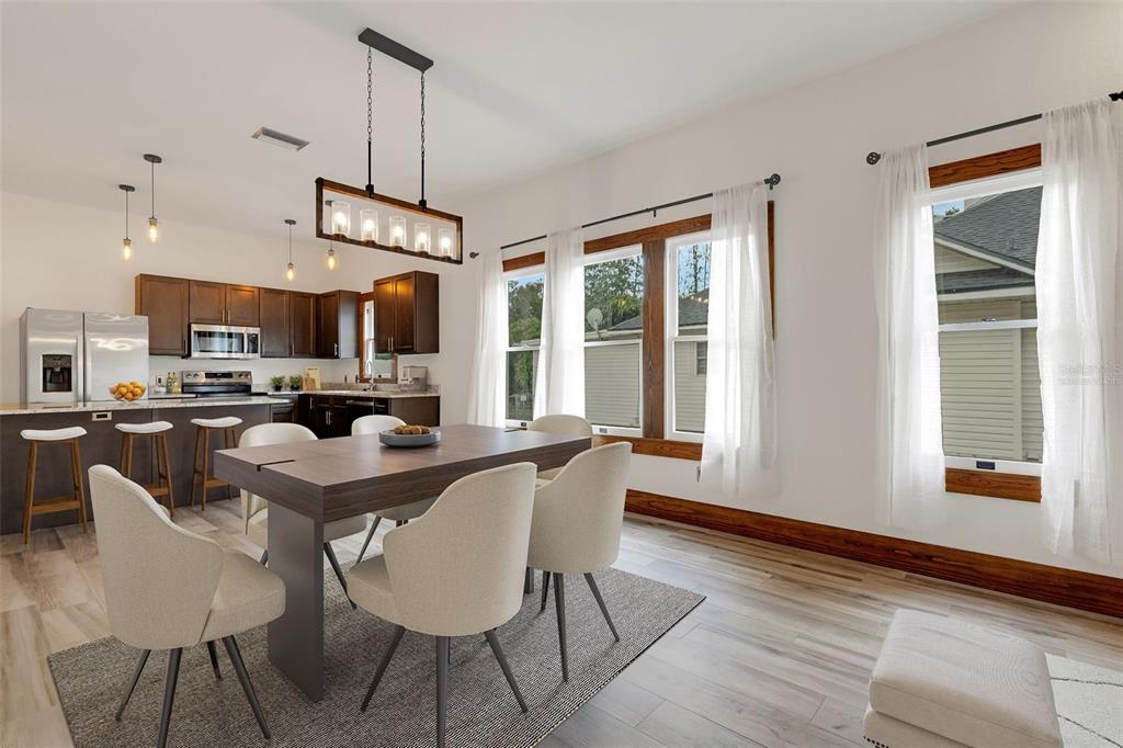A dining area with a wooden table, upholstered chairs, and an adjacent kitchen with dark cabinets — 711 E LIME STREET, LAKELAND, FL