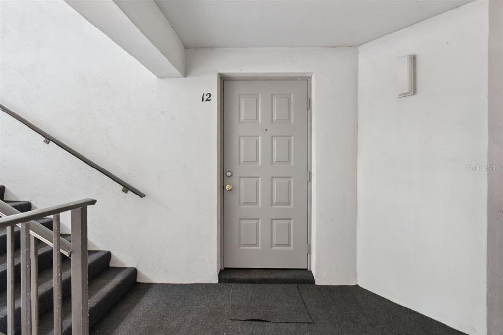 A gray front door with the number 12 is located next to a stairwell — 8215 SUN SPRING CIRCLE UNIT 12, ORLANDO, FL