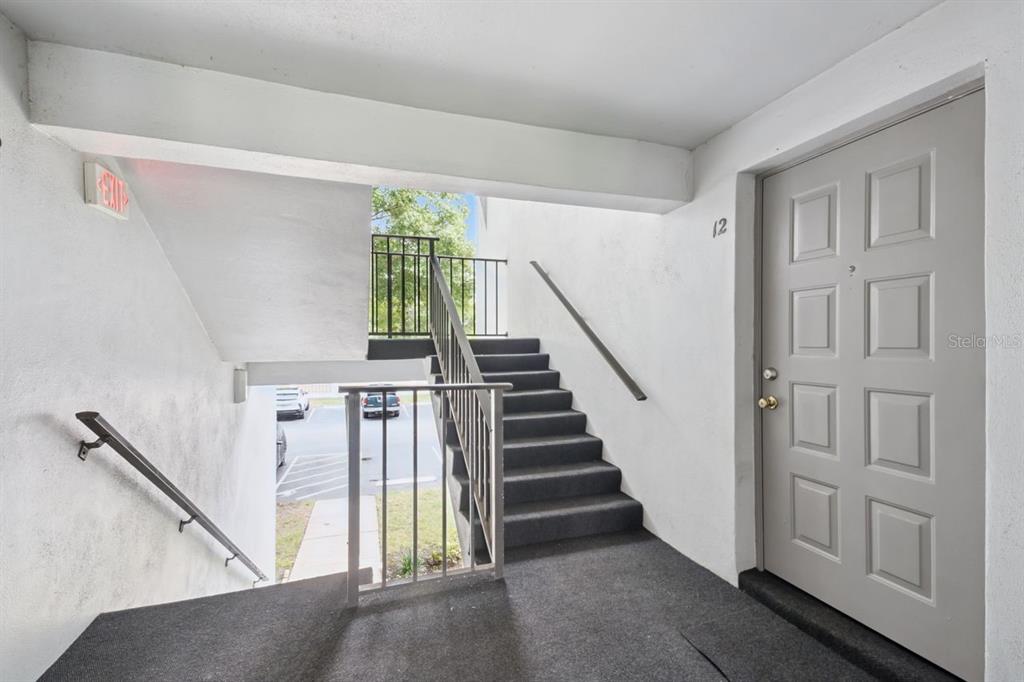 A gray door labeled 12 sits at the top of a concrete outdoor staircase — 8215 SUN SPRING CIRCLE UNIT 12, ORLANDO, FL