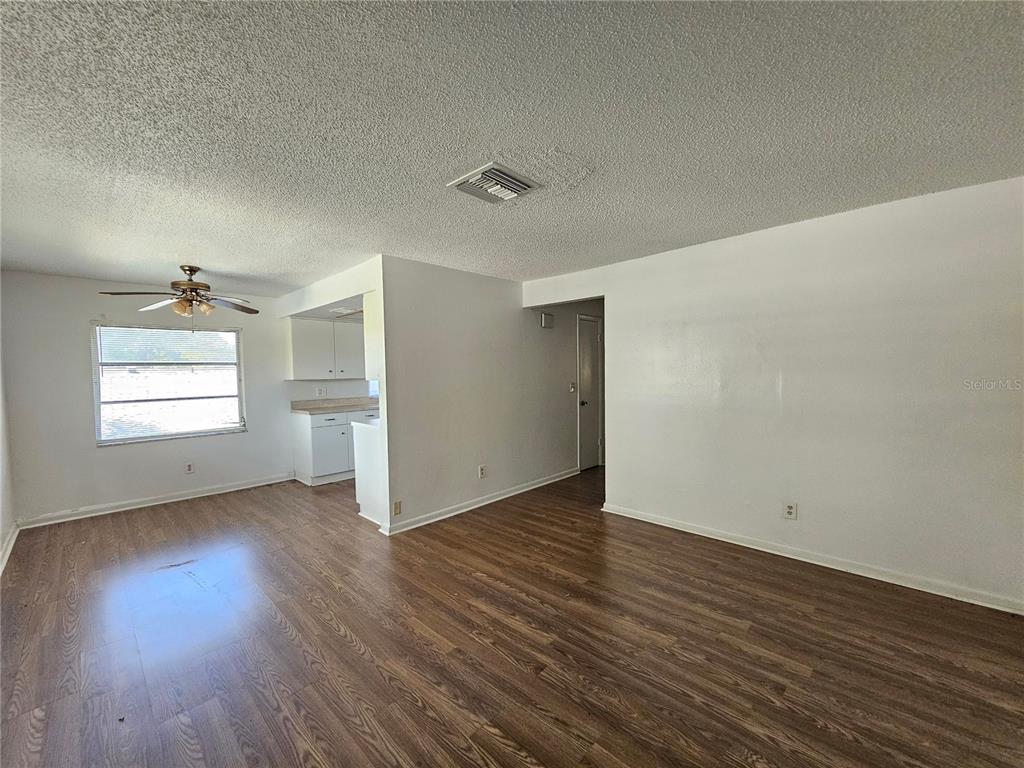An open-concept living area features wood-look flooring, white walls, and a ceiling fan — 209 NW JEFFERSON CIRCLE N UNIT 13, ST PETERSBURG, FL