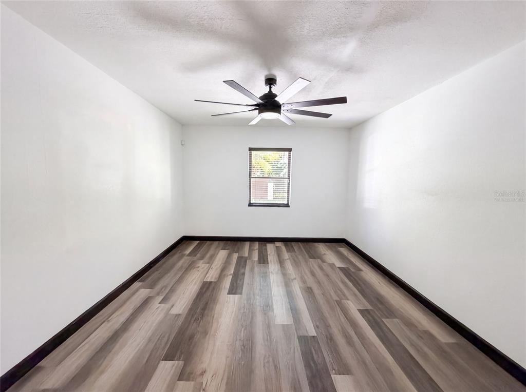 An empty room features white walls, a ceiling fan, and wood-look plank flooring — 1515 S WEST SHORE BOULEVARD, TAMPA, FL