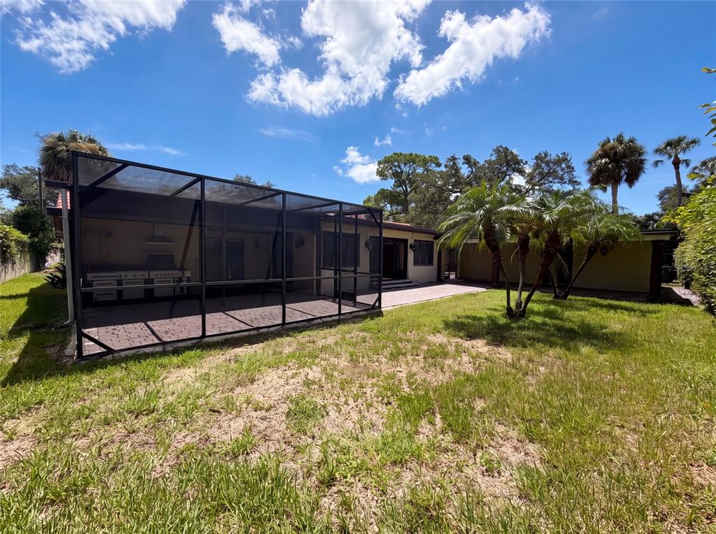 A backyard view shows a house with a screened-in patio and a grassy lawn — 1515 S WEST SHORE BOULEVARD, TAMPA, FL