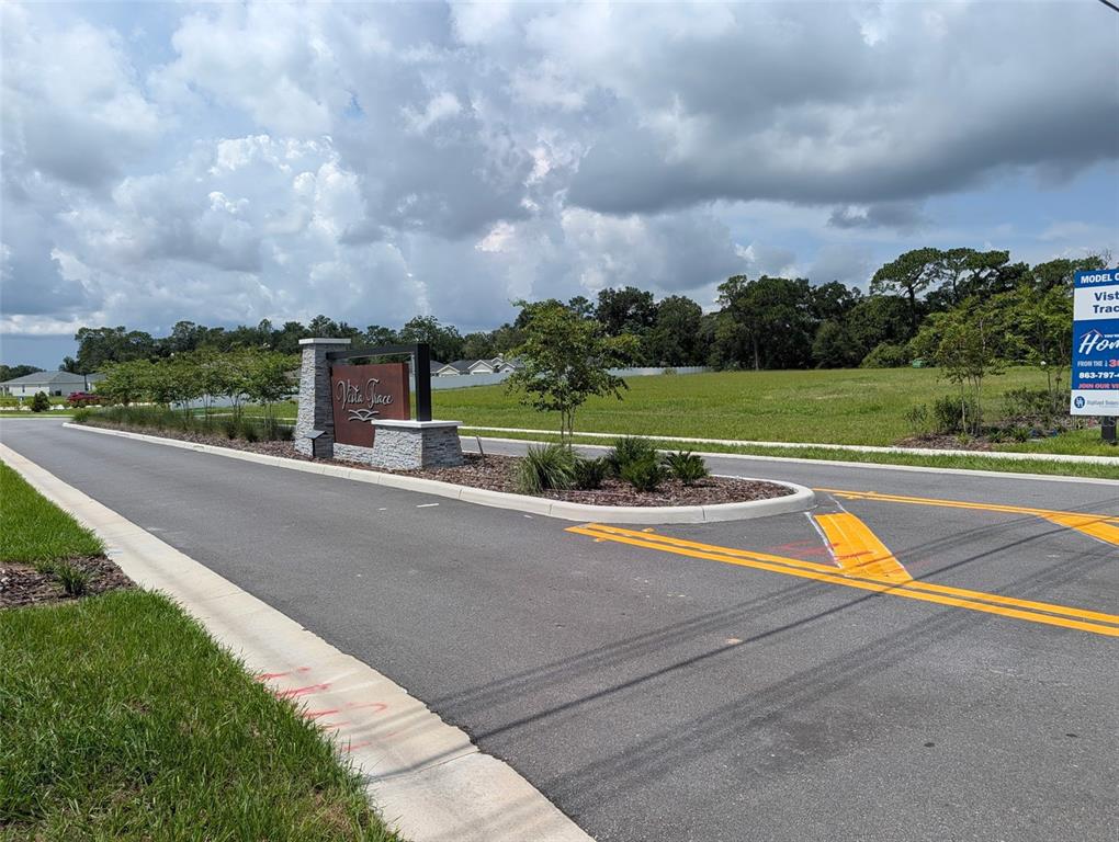 A stone monument sign marks the entrance to a residential development with a grassy lot — EAST HWY 25, BELLEVIEW, FL