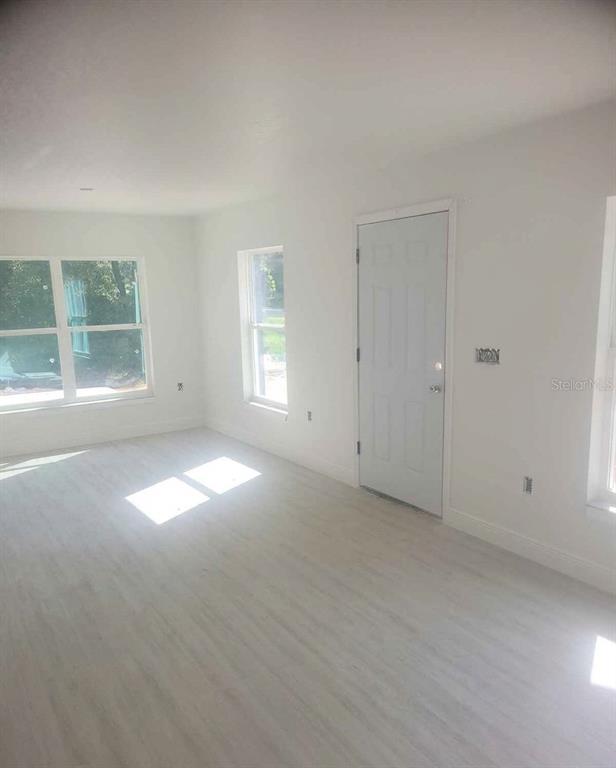 An interior view of a room with white walls, light-colored flooring, and several windows — 338 2ND WAY, INTERLACHEN, FL
