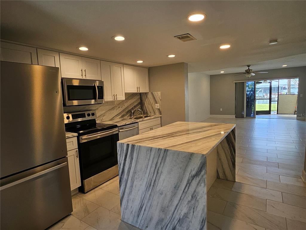 A modern kitchen features white cabinets, stainless steel appliances, and a marble-topped waterfall island — 1028 APOLLO BEACH BOULEVARD UNIT 19, APOLLO BEACH, FL