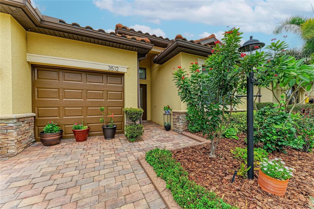 A paved driveway leads to a garage and front entrance of a stucco house — 3512 SAVANNA PALMS COURT, LAKEWOOD RANCH, FL