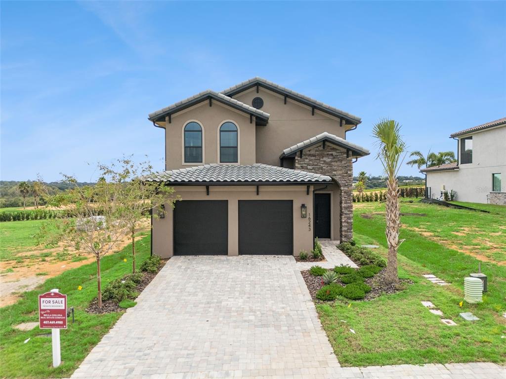A digital rendering of a two-story suburban house with a two-car garage and palm trees — 16243 VETTA DRIVE, MONTVERDE, FL