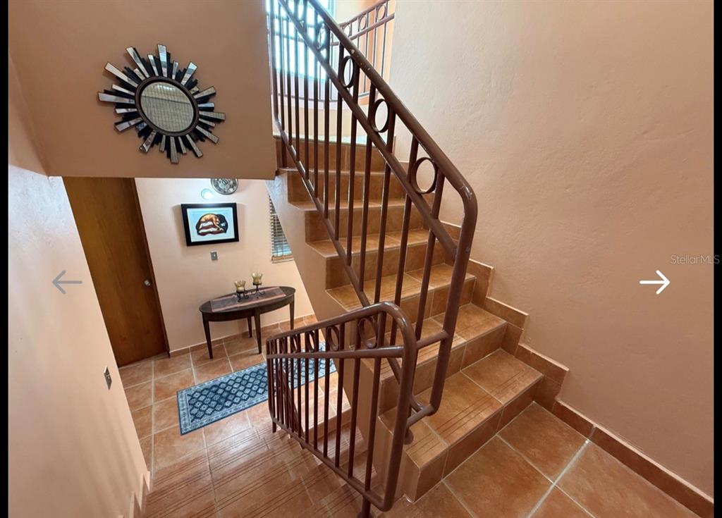 A staircase with brown metal railings leads up from a tiled landing with decor — The Village at the Hill FLAMENCO UNIT 50, CEIBA, PR