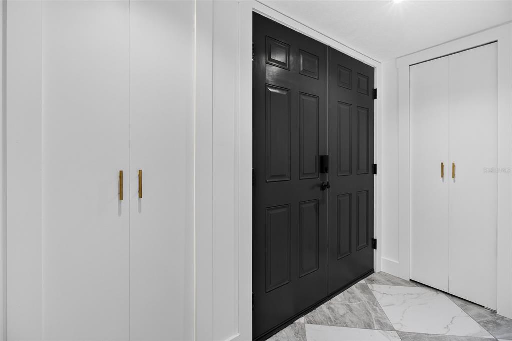 An entryway features a black double door, white cabinetry with gold handles, and marble flooring — 1 WINDRUSH BOULEVARD UNIT 65, INDIAN ROCKS BEACH, FL