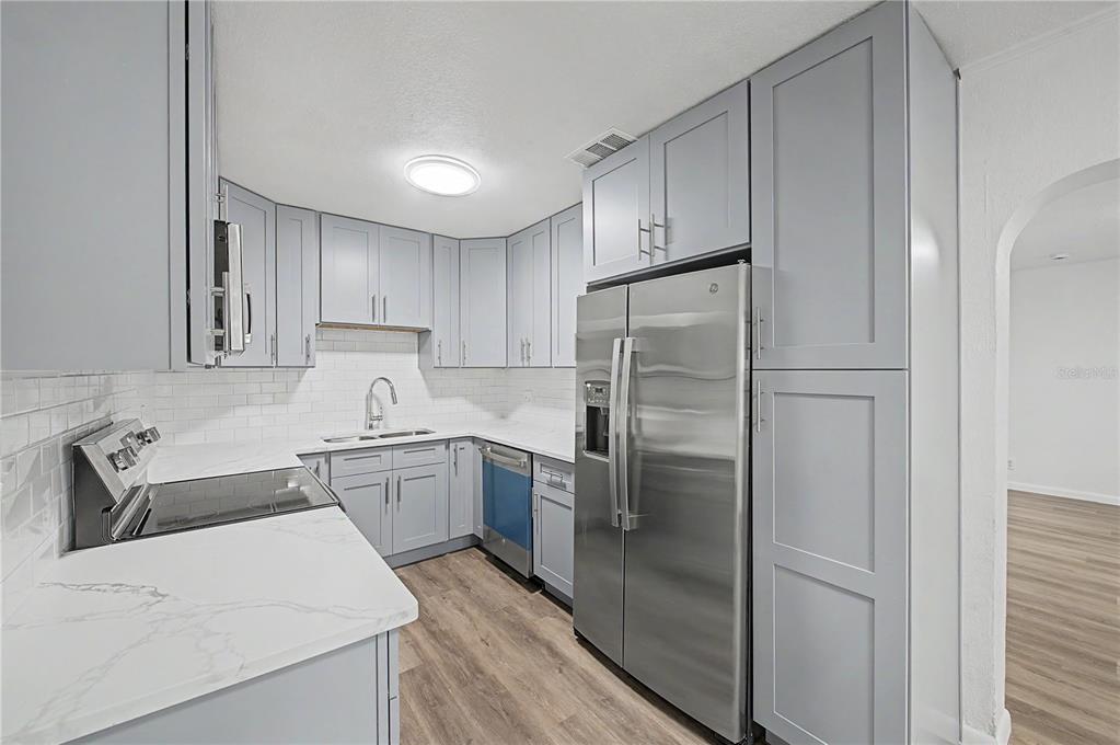 A kitchen features light gray cabinets, stainless steel appliances, white countertops, and white subway tile — 810 E 120TH AVENUE, TAMPA, FL