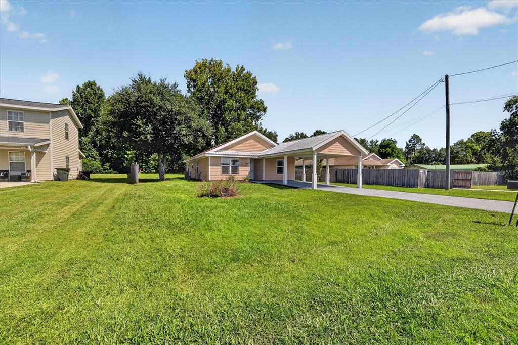 A single-story house with a carport and a large front lawn under a blue sky — 237 NE GUM SWAMP ROAD, LAKE CITY, FL