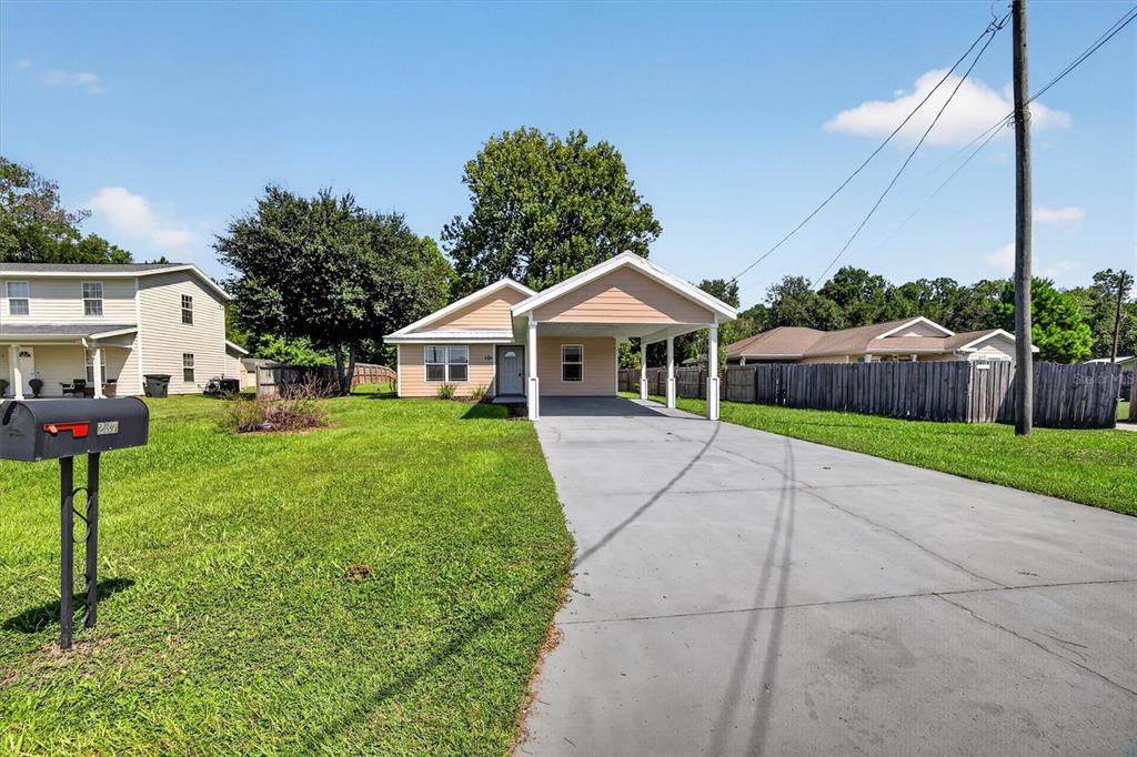 A single-story house with a carport and a concrete driveway sits on a grassy lot — 237 NE GUM SWAMP ROAD, LAKE CITY, FL