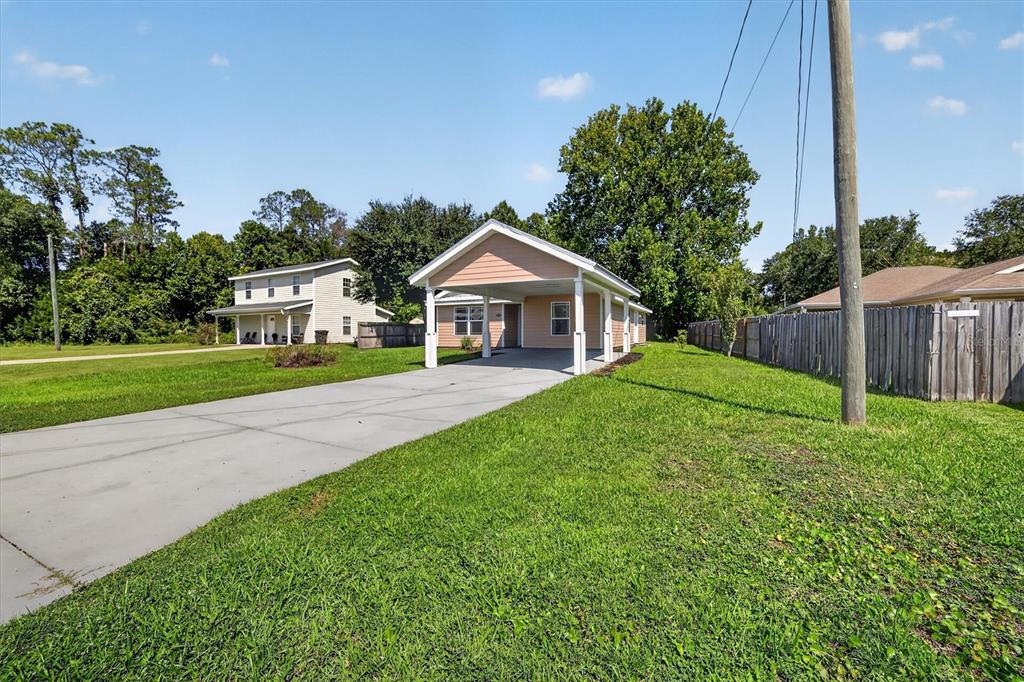 A peach-colored house with a front carport sits on a grassy lot with a driveway — 237 NE GUM SWAMP ROAD, LAKE CITY, FL