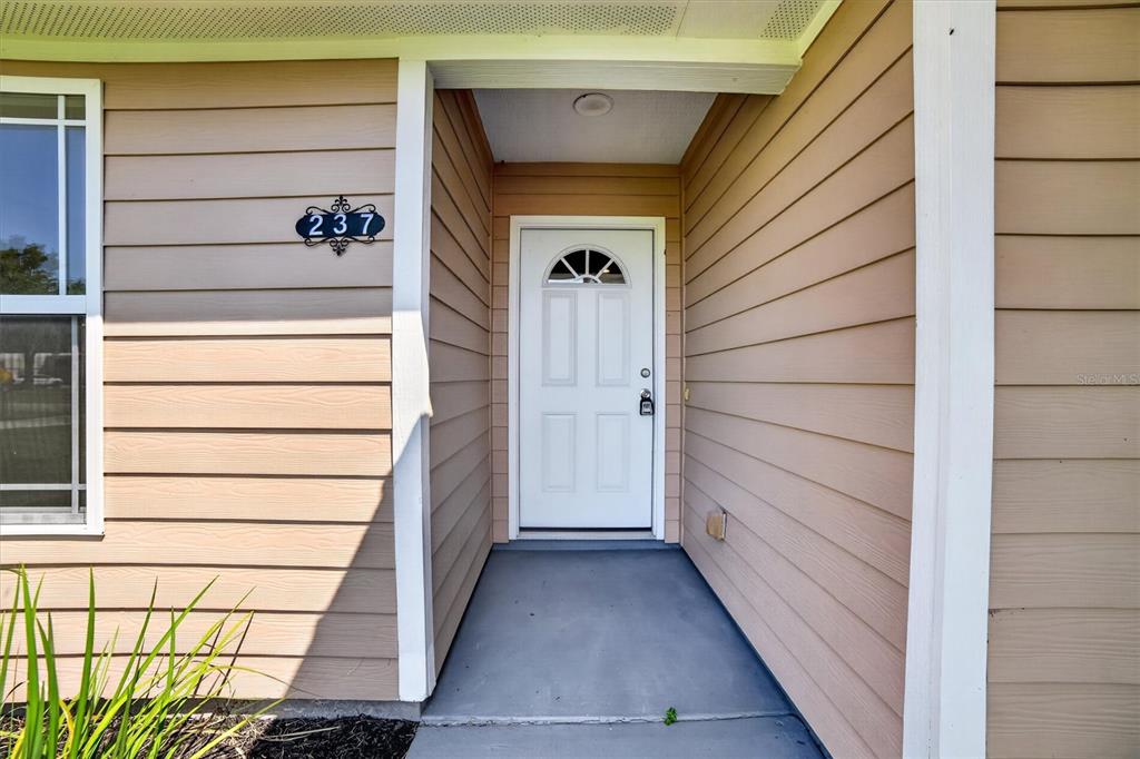 The exterior view shows a tan-sided house entrance with a white door and house number 237 — 237 NE GUM SWAMP ROAD, LAKE CITY, FL