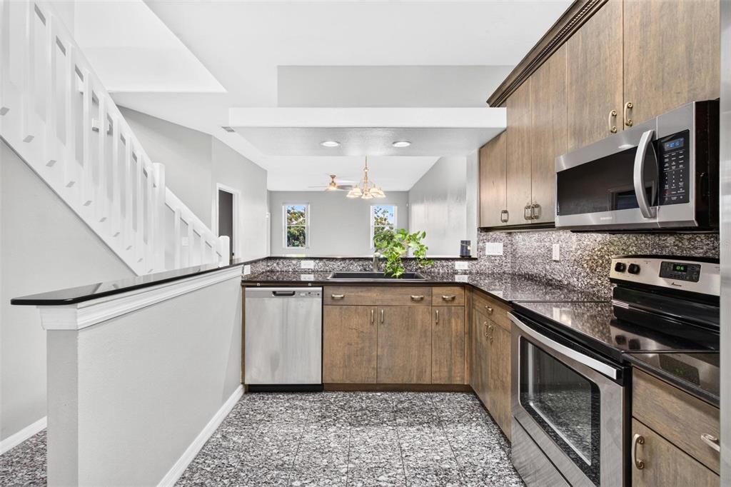 A two-story townhouse exterior features a beige stucco facade, a garage, and a landscaped hedge — 6400 46TH AVENUE N UNIT 16, KENNETH CITY, FL