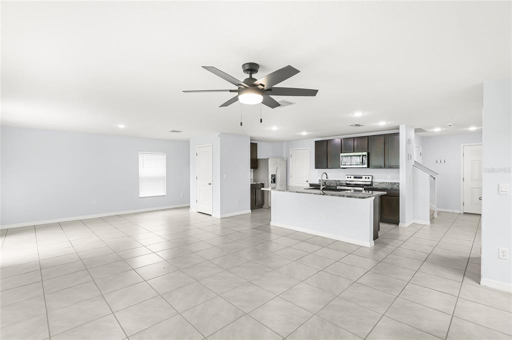 An open-concept kitchen and living area features light tile flooring, dark cabinetry, and a ceiling fan — 10116 CHARLOTTE DRIVE, PARRISH, FL