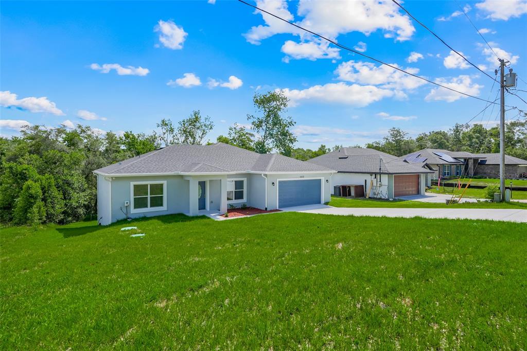 A single-story house with a gray exterior, a two-car garage, and a concrete driveway — 1622 N MERRICK DRIVE, DELTONA, FL