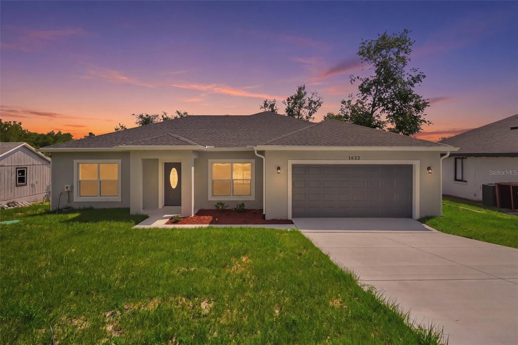 A single-story house with a gray exterior, blue garage door, and a concrete driveway — 1622 N MERRICK DRIVE, DELTONA, FL