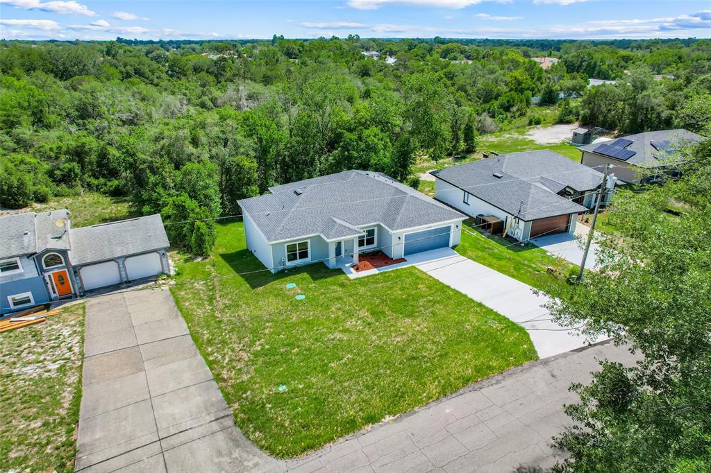 A single-story light gray house with a two-car garage sits on a grassy lot — 1622 N MERRICK DRIVE, DELTONA, FL