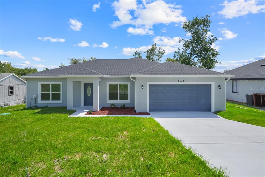A single-story house with a blue garage door, gray roof, and a concrete driveway — 1622 N MERRICK DRIVE, DELTONA, FL