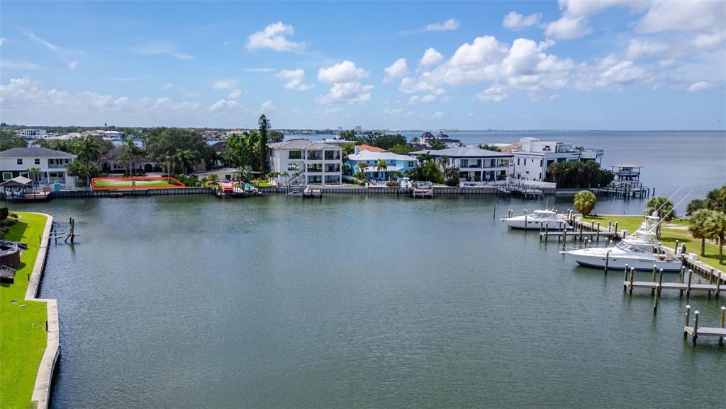 A waterfront view of a canal with a bulkhead, palm trees, and residential houses — 52 SANDPIPER ROAD, TAMPA, FL