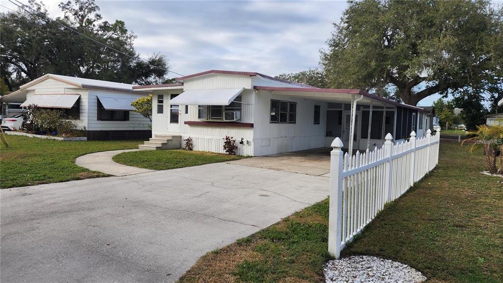 A white mobile home with a carport, concrete driveway, and white picket fence — 196 SUNSET DRIVE, LAKE ALFRED, FL
